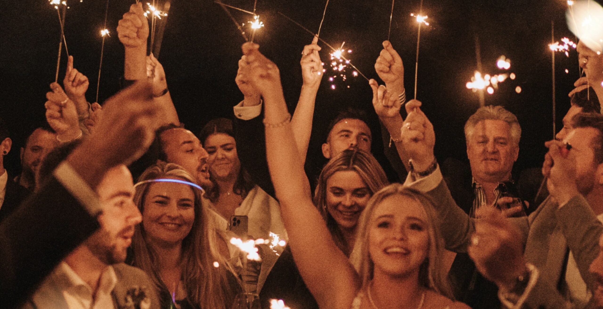 Crowd of people holding up sparklers at Coombe's affordable wedding venue