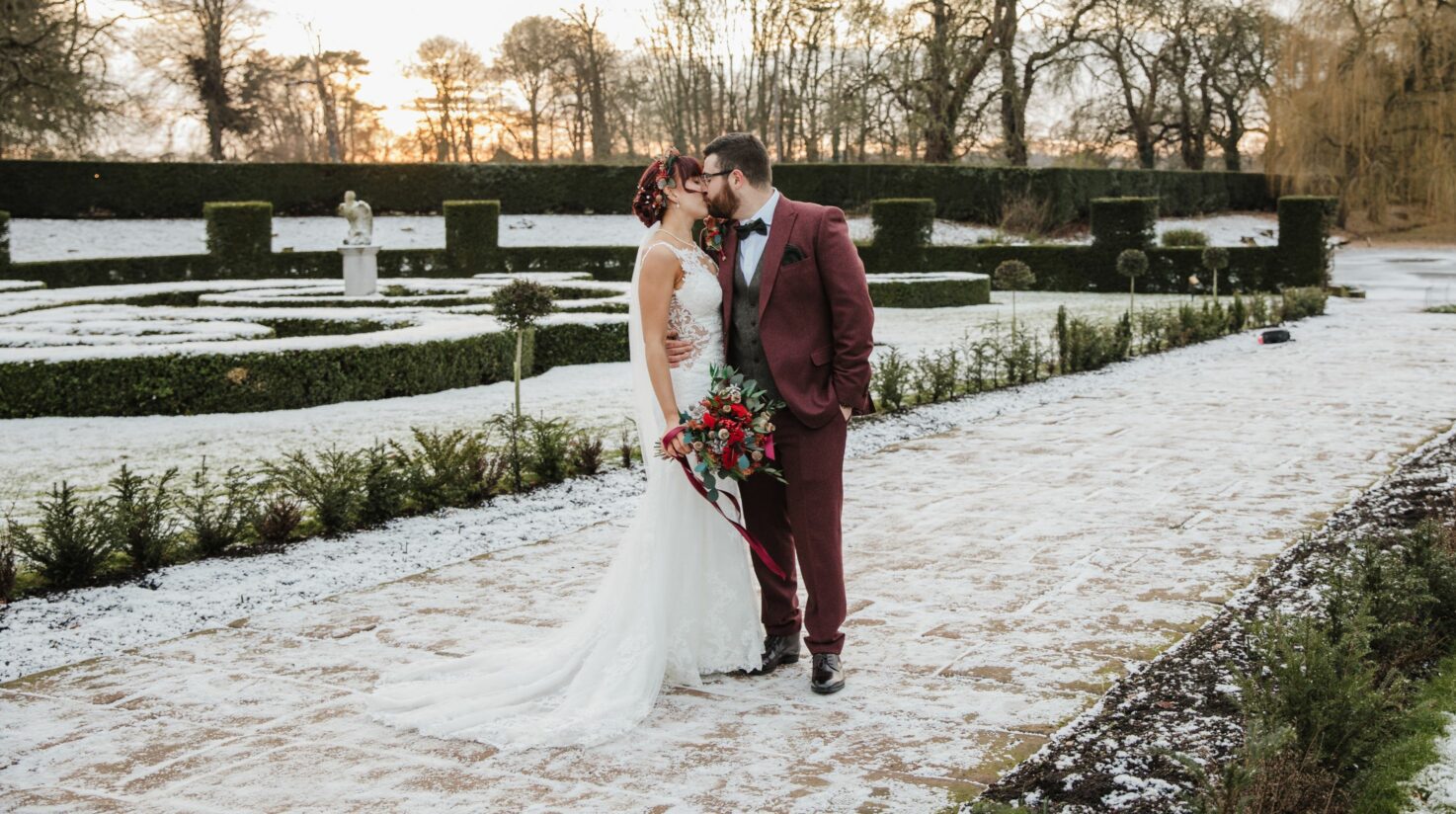 Bride and groom stand surrounded by snow-topped lawns - Coombe's affordable wedding venue